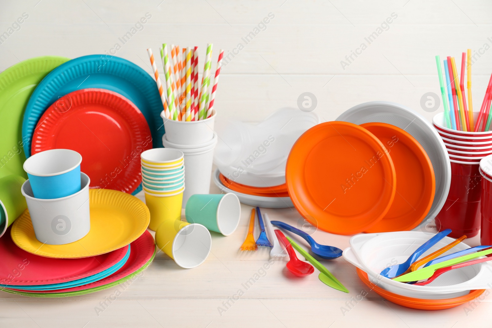 Photo of Set of disposable tableware on white wooden table