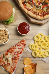 French fries, pizza and other fast food on wooden table, flat lay