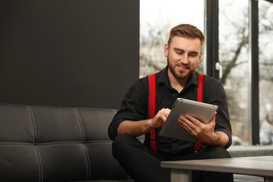 Photo of Young business owner with tablet on couch indoors
