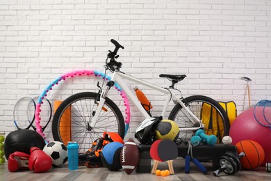 Photo of Bicycle and different sport equipment near white brick wall