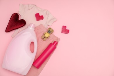 Photo of Bottles of laundry detergents, baby clothes, toy bear and decorative hearts on pink background, flat lay. Space for text