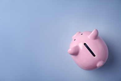 Pink piggy bank on color background, top view