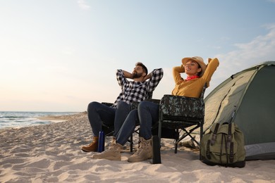 Photo of Couple resting near camping tent on beach