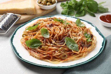 Photo of Delicious pasta with anchovies, olives and basil on white table