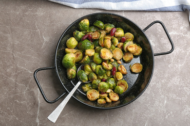 Photo of Delicious roasted brussels sprouts with red beans and peanuts on grey marble table, top view