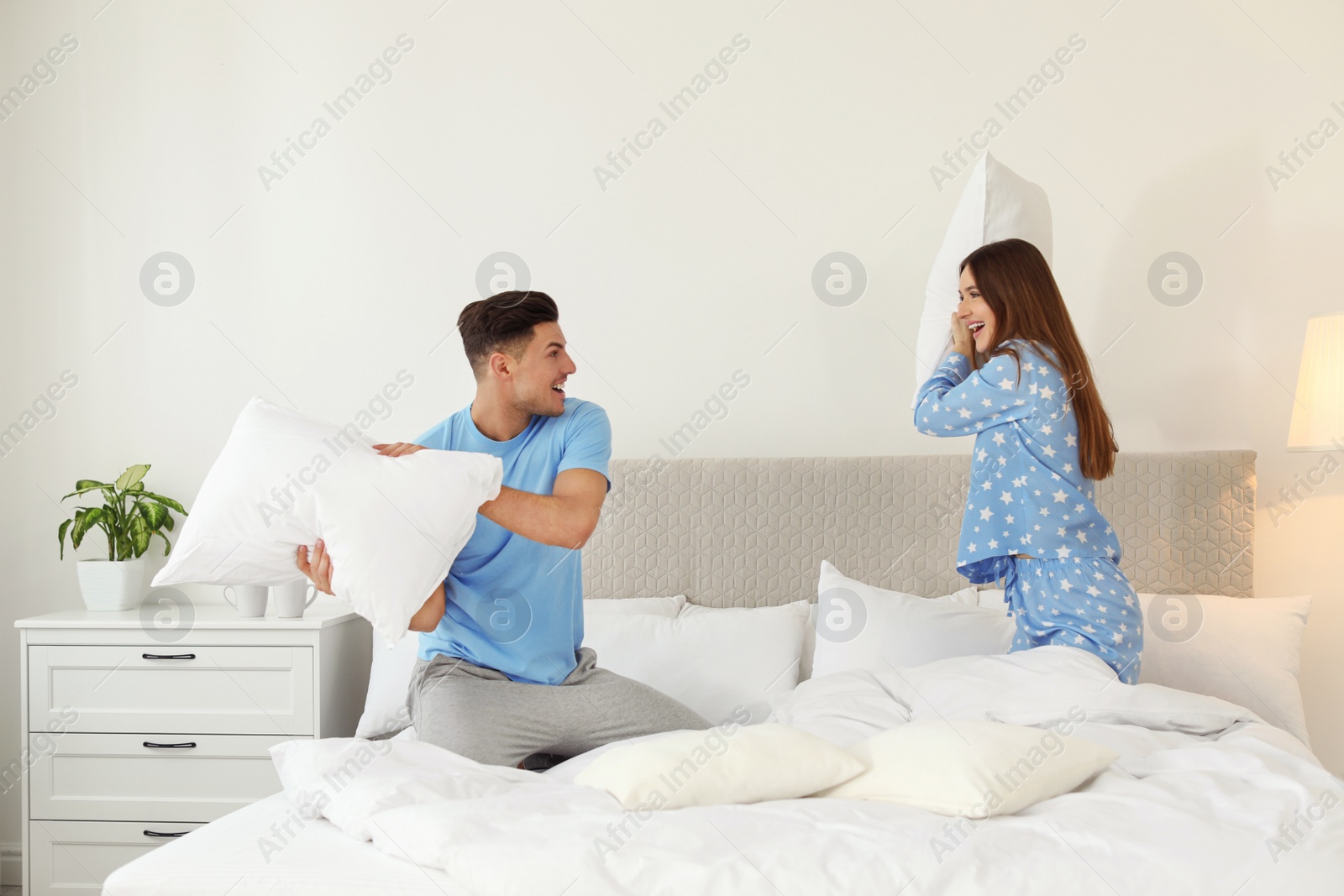 Photo of Happy couple having pillow fight in bedroom