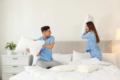 Happy couple having pillow fight in bedroom