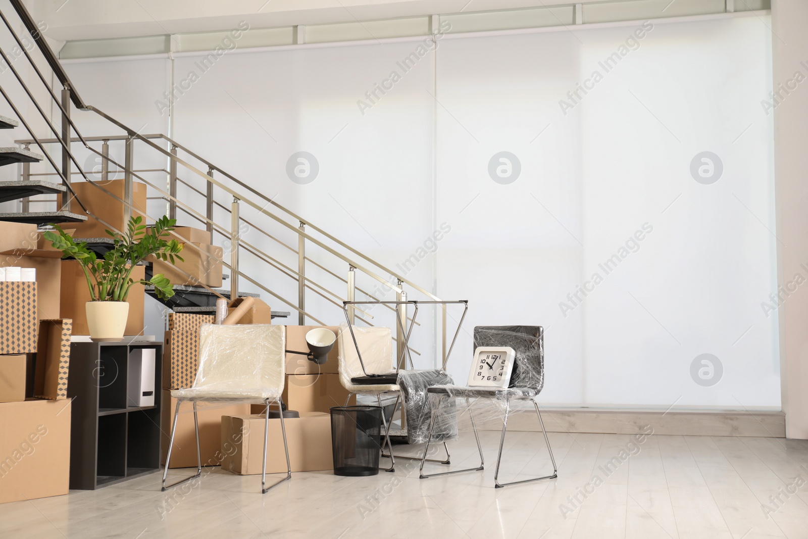 Photo of Cardboard boxes and packed stuff near stairs in office, space for text. Moving day