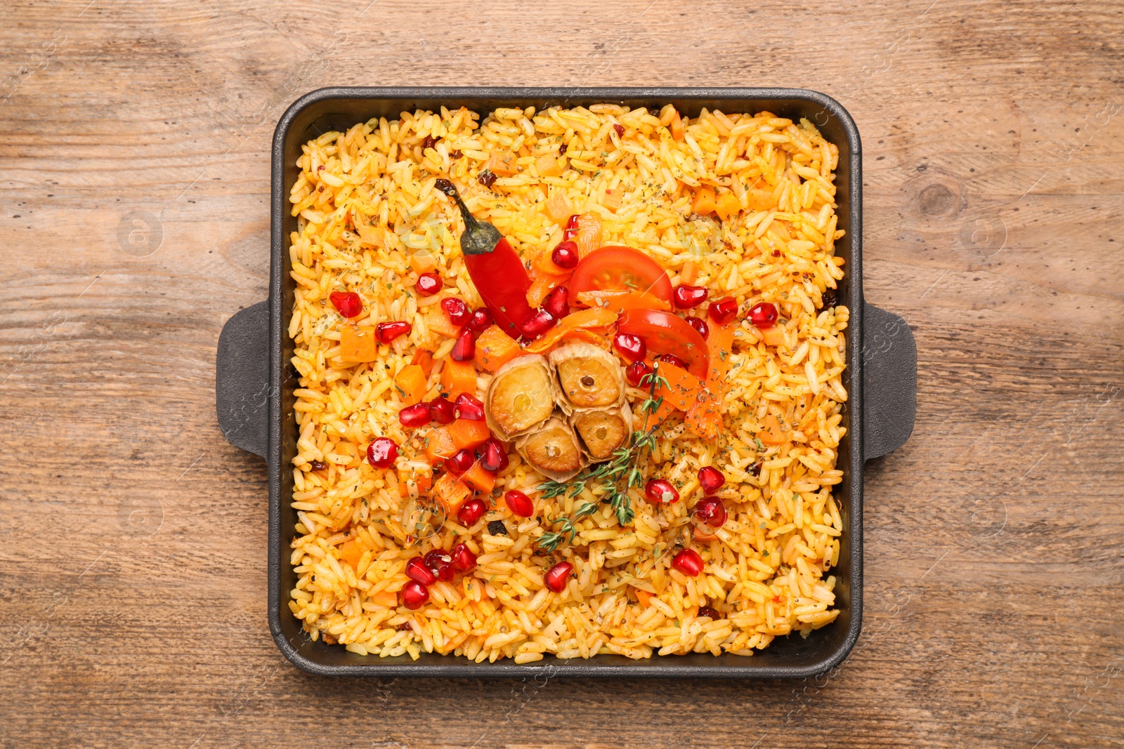 Photo of Tasty rice pilaf with vegetables on wooden table, top view