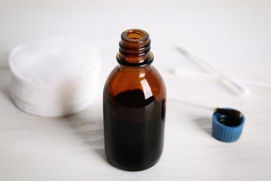 Photo of Bottle of medical iodine, cotton pads and buds on white wooden table, closeup