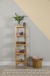 Shelving unit with toiletries near light wall indoors. Bathroom interior element