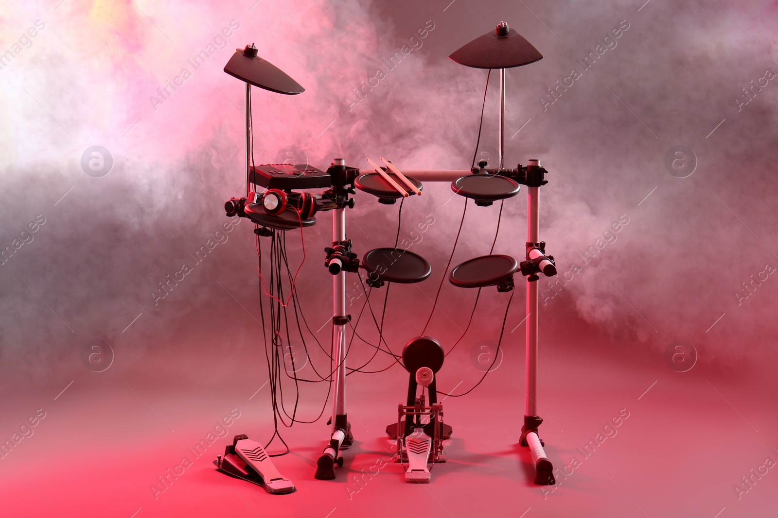 Photo of Modern electronic drum kit and smoke on grey background, toned in pink. Musical instrument