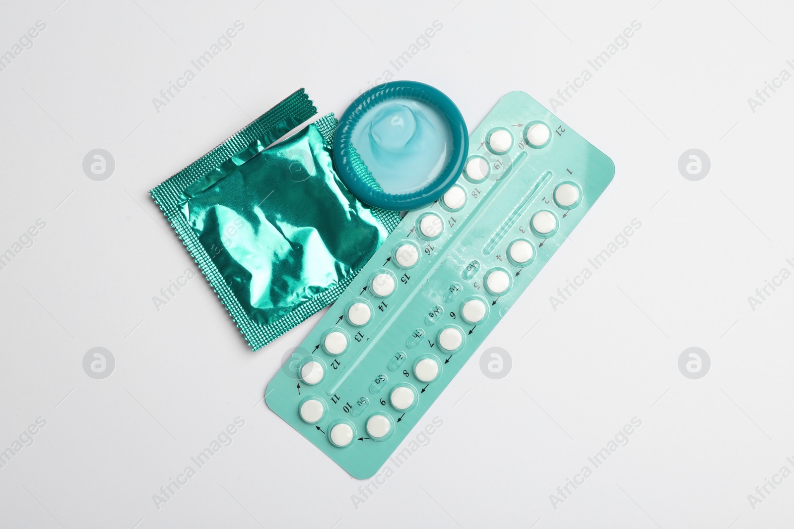 Photo of Condom and birth control pills on light grey background, flat lay. Safe sex concept