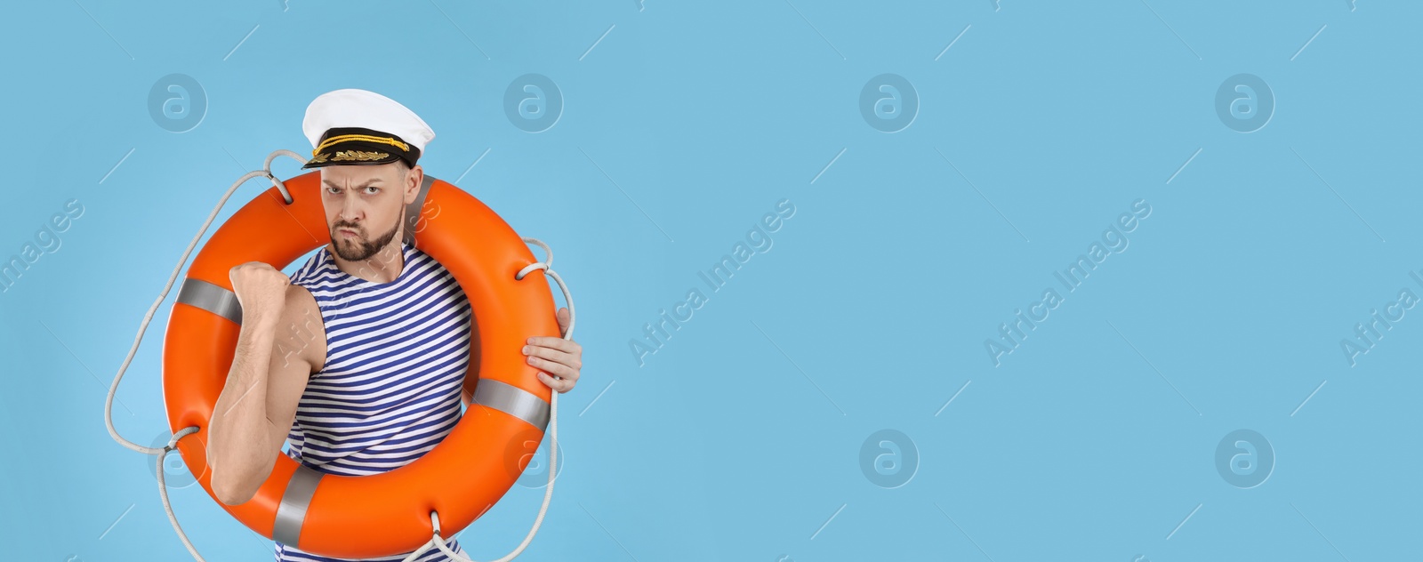 Photo of Sailor with orange ring buoy showing his strength on light blue background