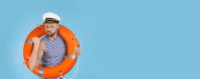 Photo of Sailor with orange ring buoy showing his strength on light blue background