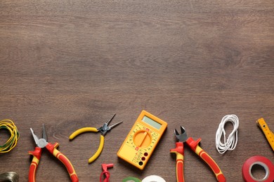 Different wires and electrician's tools on wooden table, flat lay. Space for text