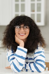 Photo of Portrait of beautiful woman with curly hair in kitchen. Attractive lady smiling and posing for camera