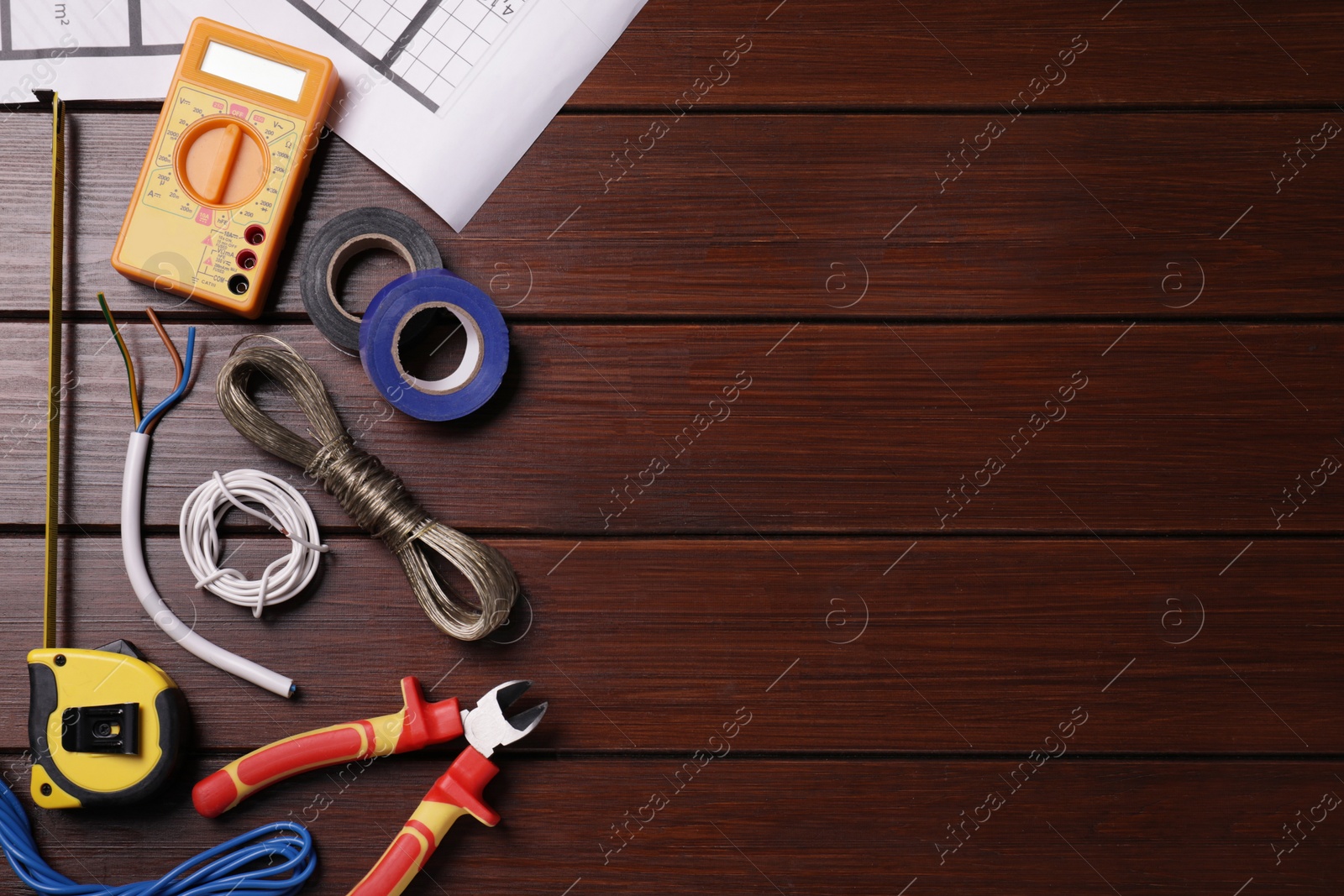 Photo of Different wires and electrician's tools on wooden table, flat lay. Space for text