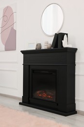 Black stylish fireplace with accessories under round mirror in cosy living room