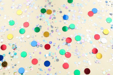 Photo of Shiny glitter on beige background, above view