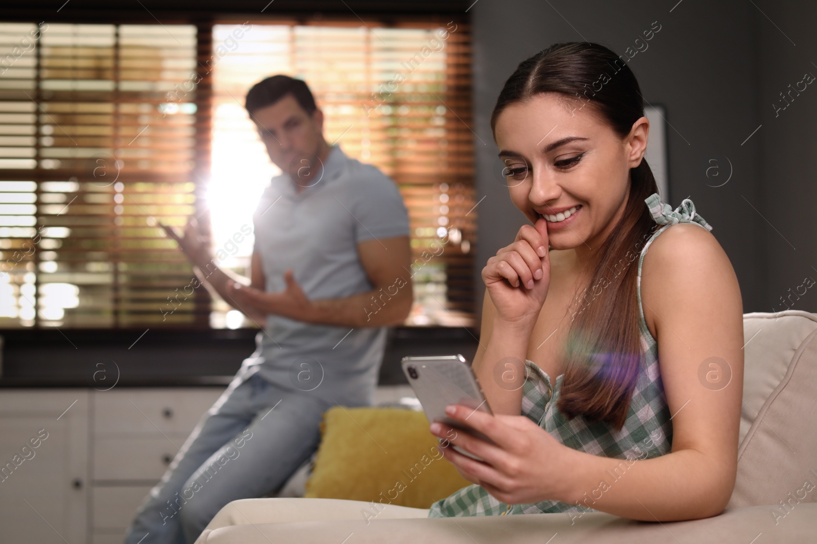 Photo of Woman preferring smartphone over spending time with her boyfriend at home. Jealousy in relationship