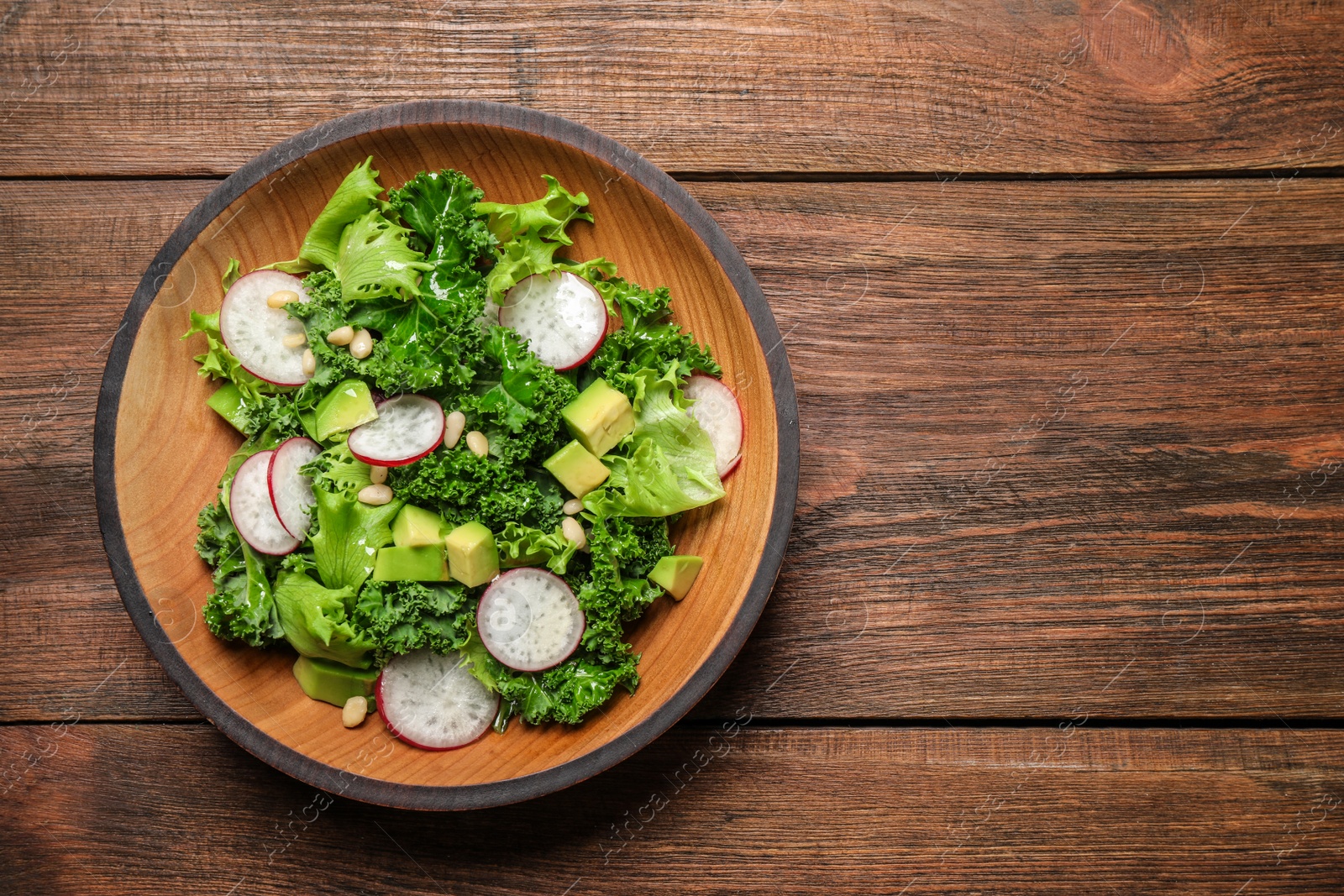 Photo of Delicious kale salad on wooden table, top view. Space for text