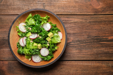 Photo of Delicious kale salad on wooden table, top view. Space for text