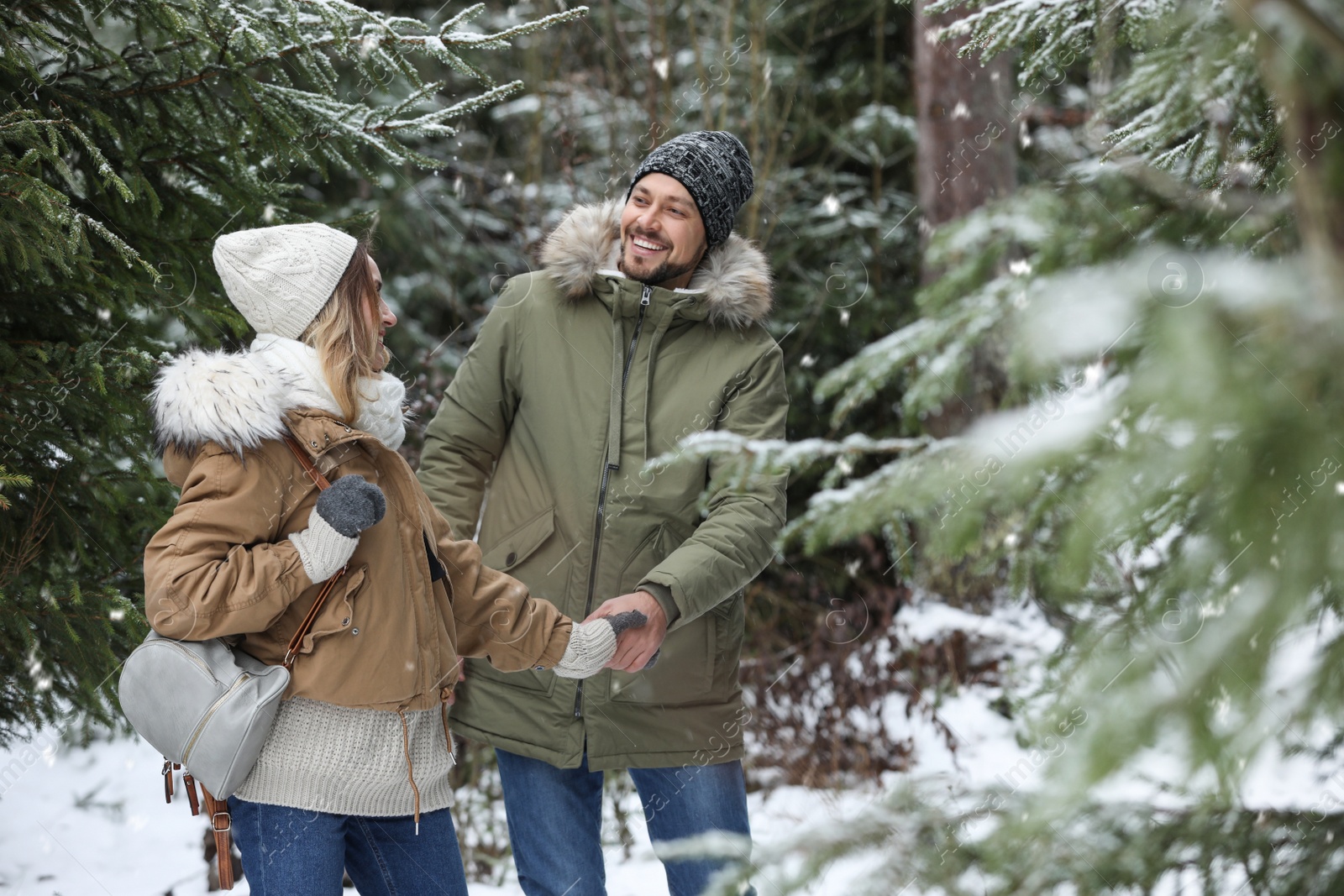 Photo of Couple in conifer forest on snowy day. Winter vacation