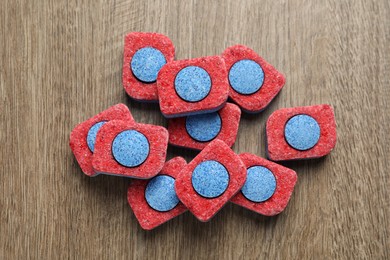 Photo of Many dishwasher detergent tablets on wooden table, flat lay