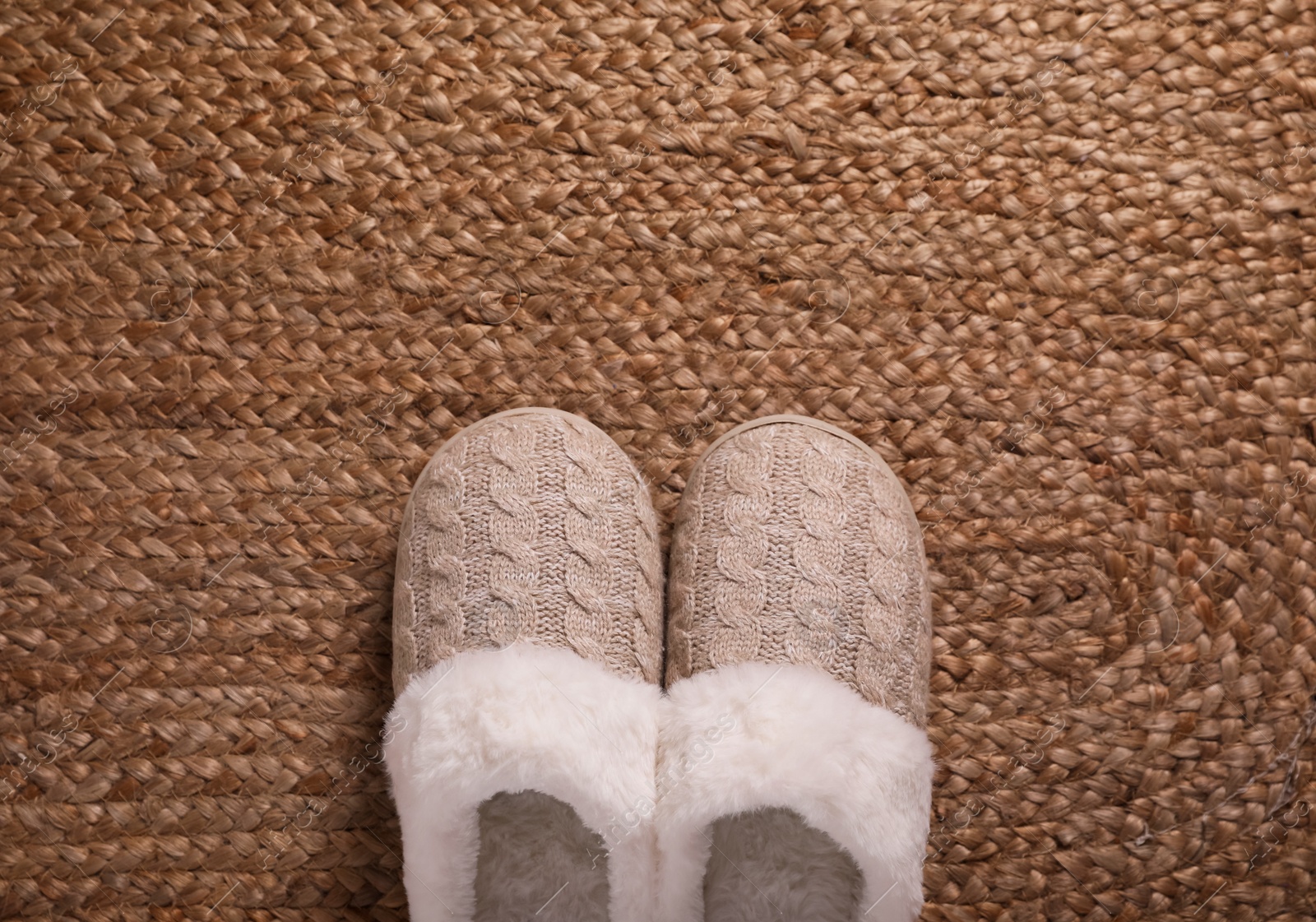 Photo of Pair of warm stylish slippers on wicker carpet, top view. Space for text