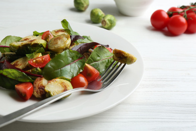 Photo of Delicious salad with roasted Brussels sprouts on white wooden table, closeup