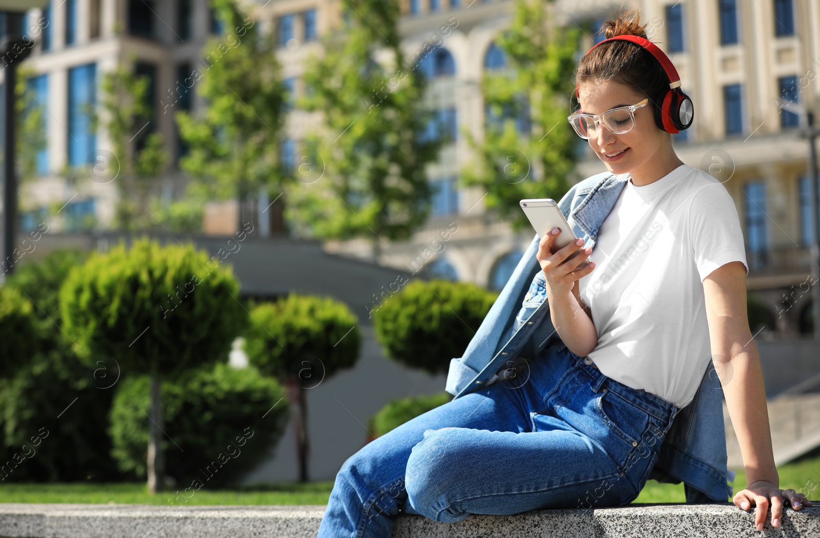 Photo of Young woman with headphones listening to music on city street. Space for text