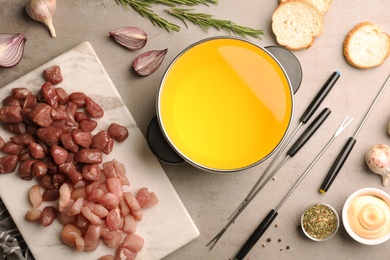 Photo of Flat lay composition with oil pot and meat fondue ingredients on grey background