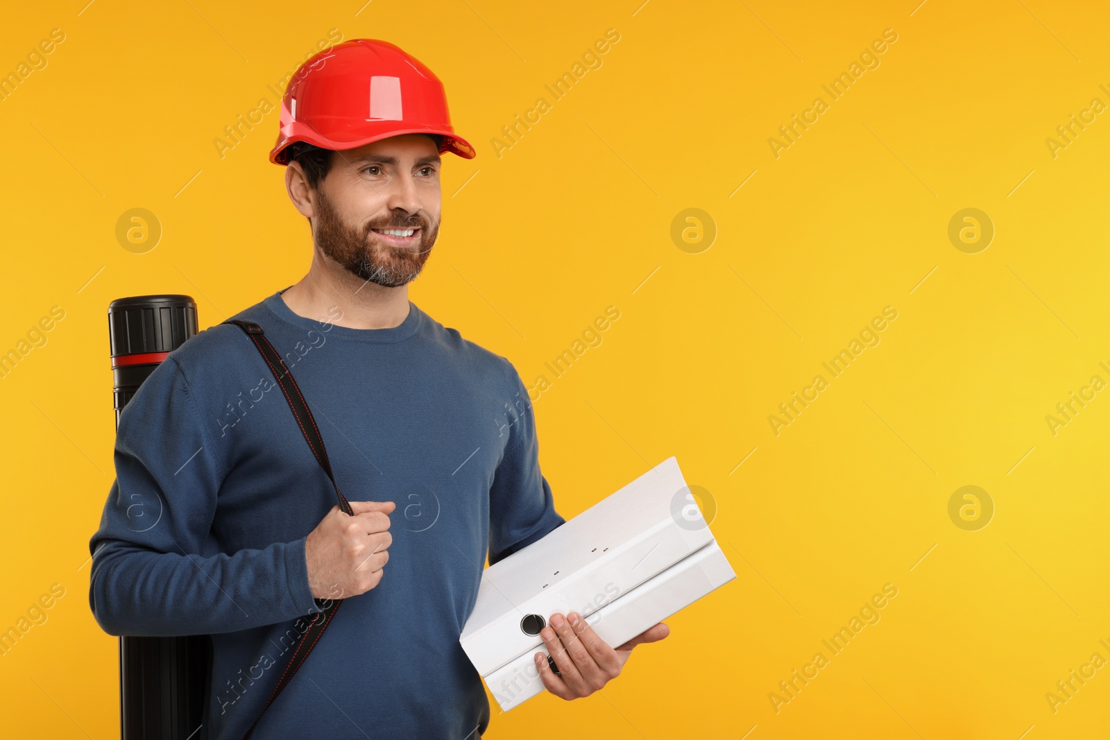 Photo of Architect in hard hat with drawing tube and folders on orange background, space for text
