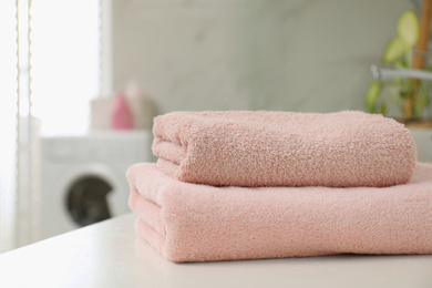 Photo of Stack of clean towels on table in laundry room