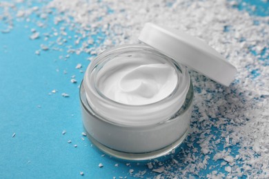 Photo of Tube of hand cream and decorative snow on light blue background. Winter skin care