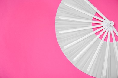 Photo of Stylish white hand fan on pink background, top view. Space for text