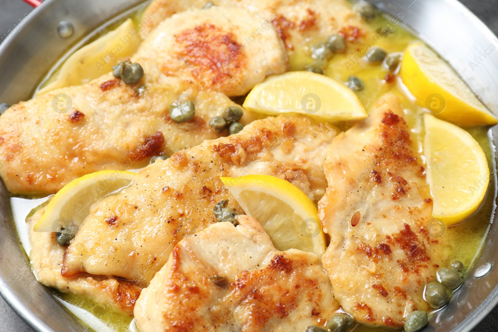 Photo of Delicious chicken piccata with lemons in pot, closeup