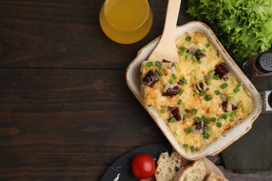 Photo of Tasty sausage casserole served on wooden table, flat lay. Space for text