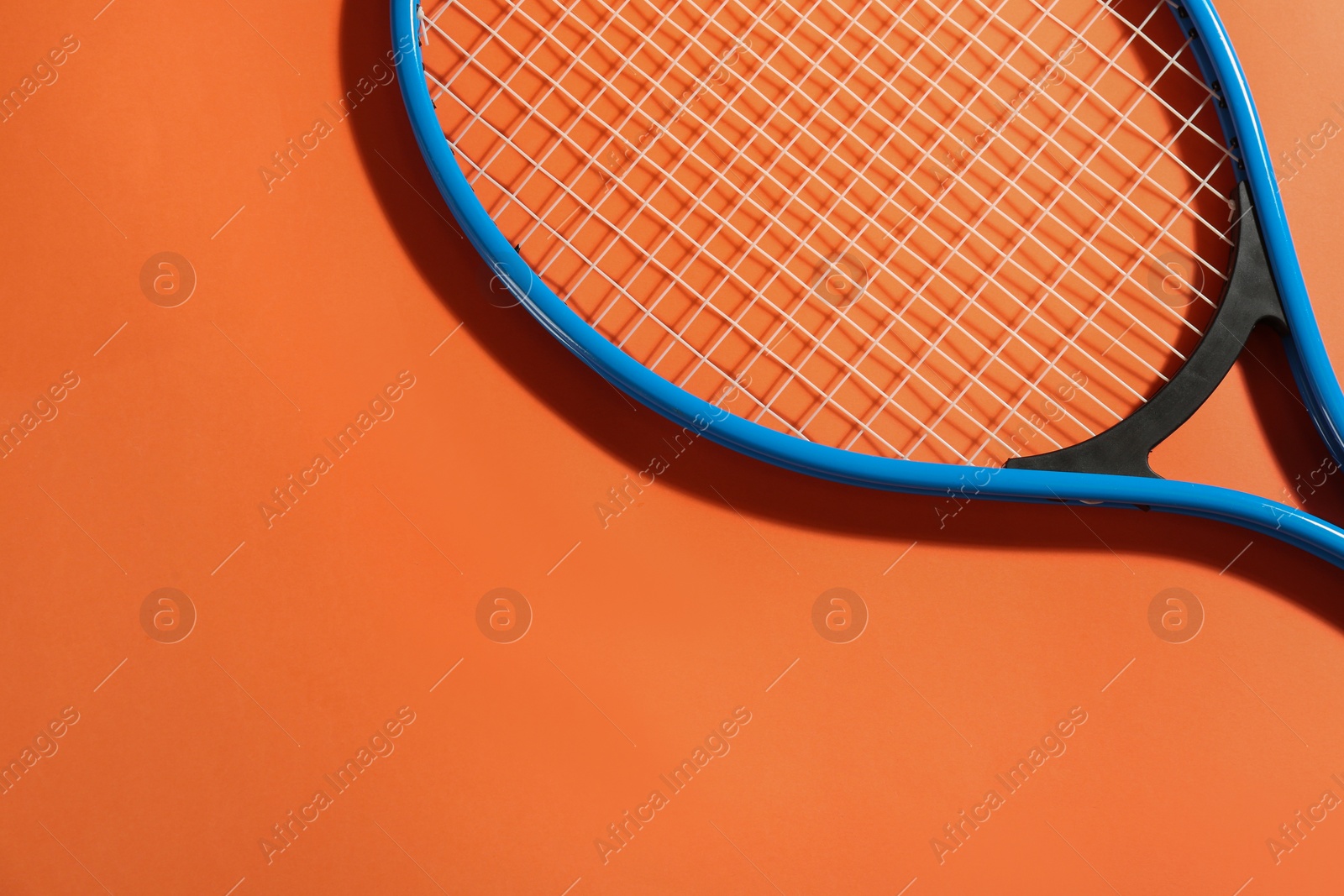 Photo of Tennis racket on orange background, top view. Space for text