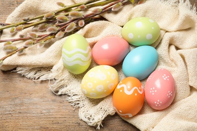 Photo of Flat lay composition with colorful painted Easter eggs on wooden table, space for text