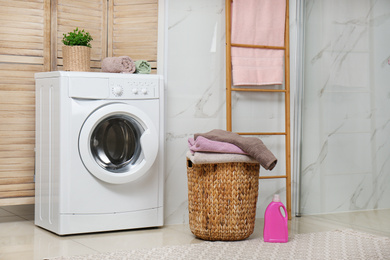 Modern washing machine and laundry in bathroom