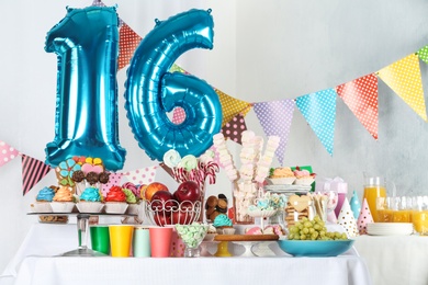 Photo of Dessert table in room decorated with blue balloons for 16 year birthday party