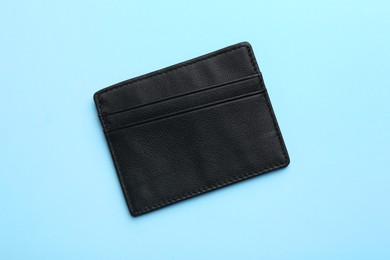 Empty leather card holder on light blue background, top view