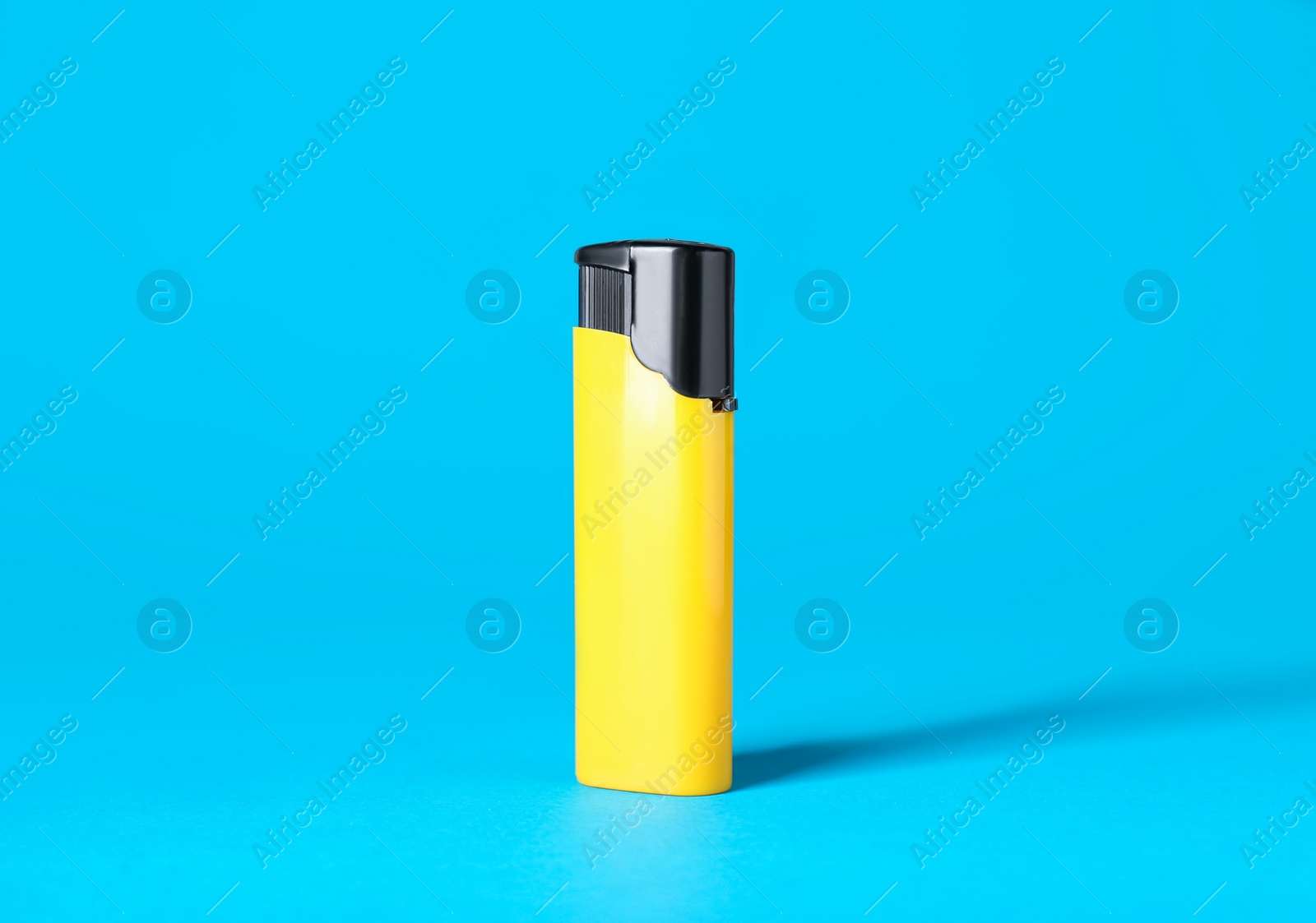 Photo of Yellow plastic cigarette lighter on light blue background
