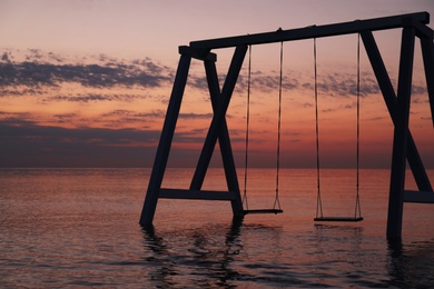 Photo of Picturesque view of swing in water on sunrise