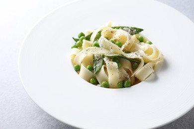 Photo of Delicious pasta with green peas on grey table, closeup