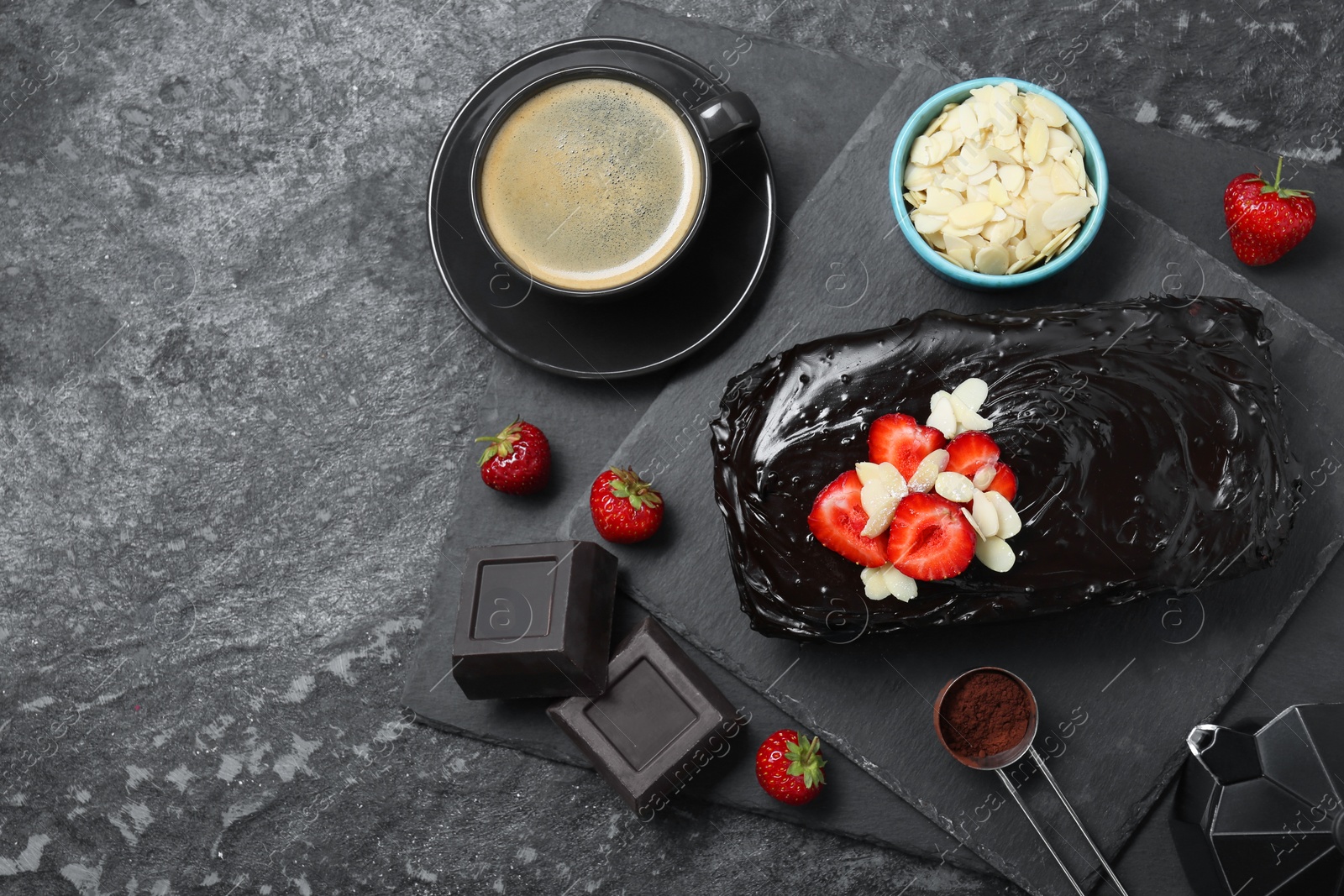 Photo of Delicious chocolate sponge cake, coffee and ingredients on black table, flat lay