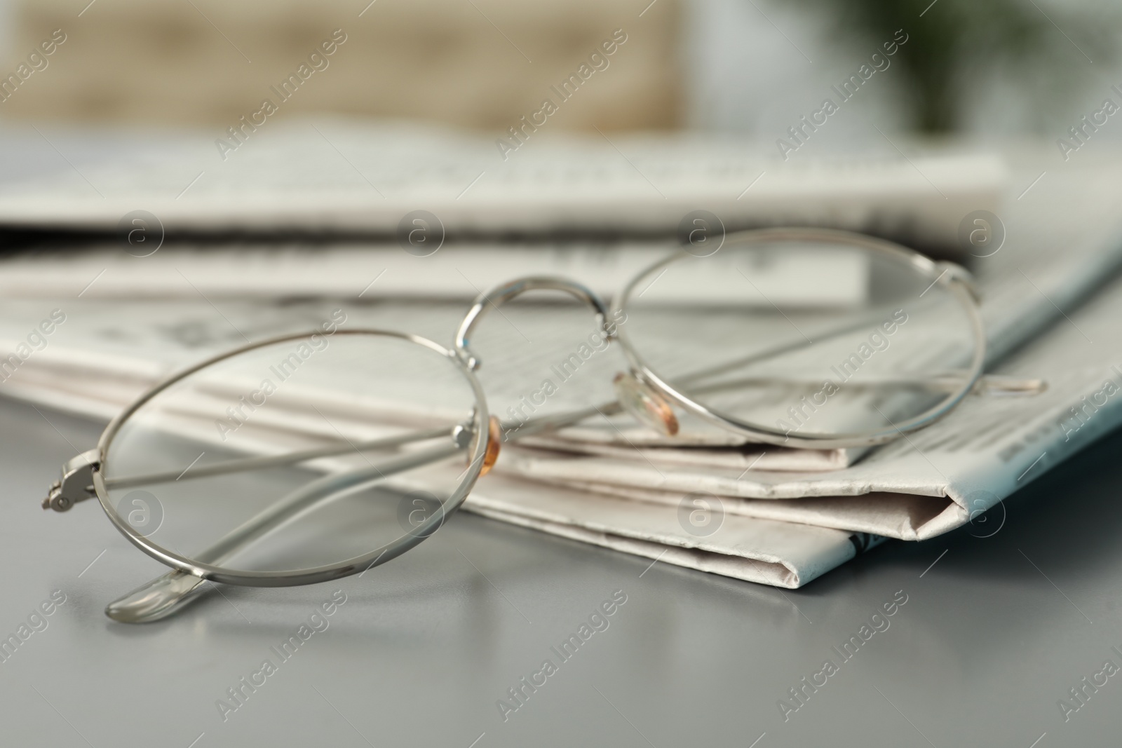 Photo of Newspapers and glasses on grey table, closeup