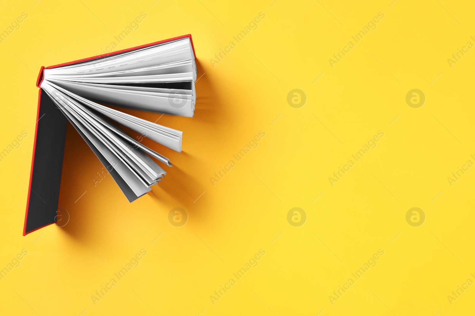 Photo of Book on yellow background, top view. Space for text